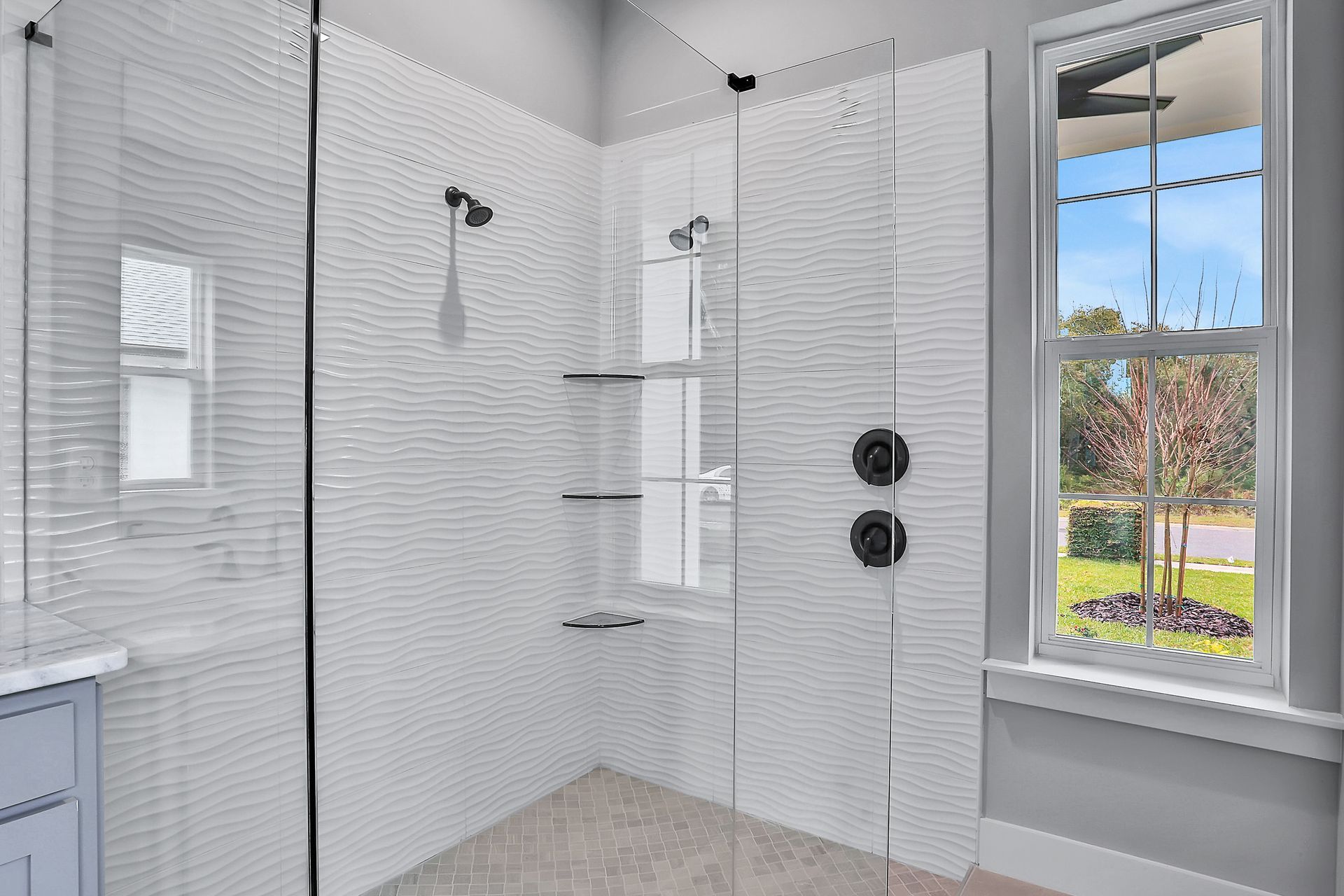 A bathroom with a walk in shower and a window.