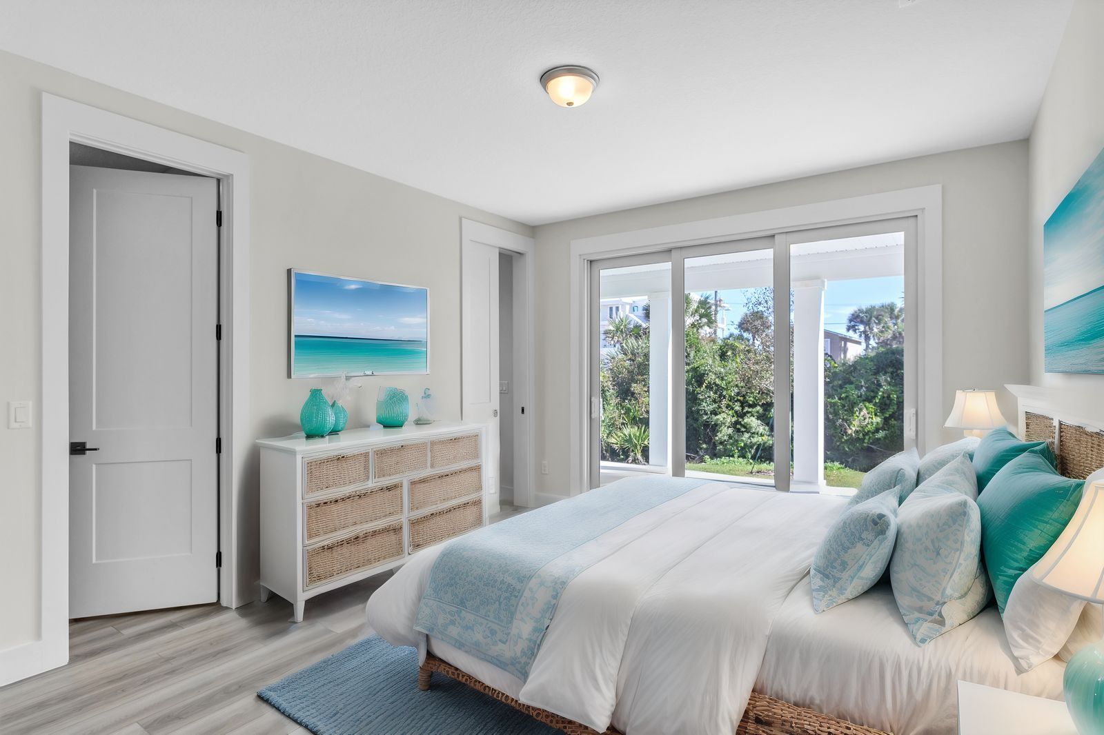 A bedroom with a king size bed , dresser , and large windows.