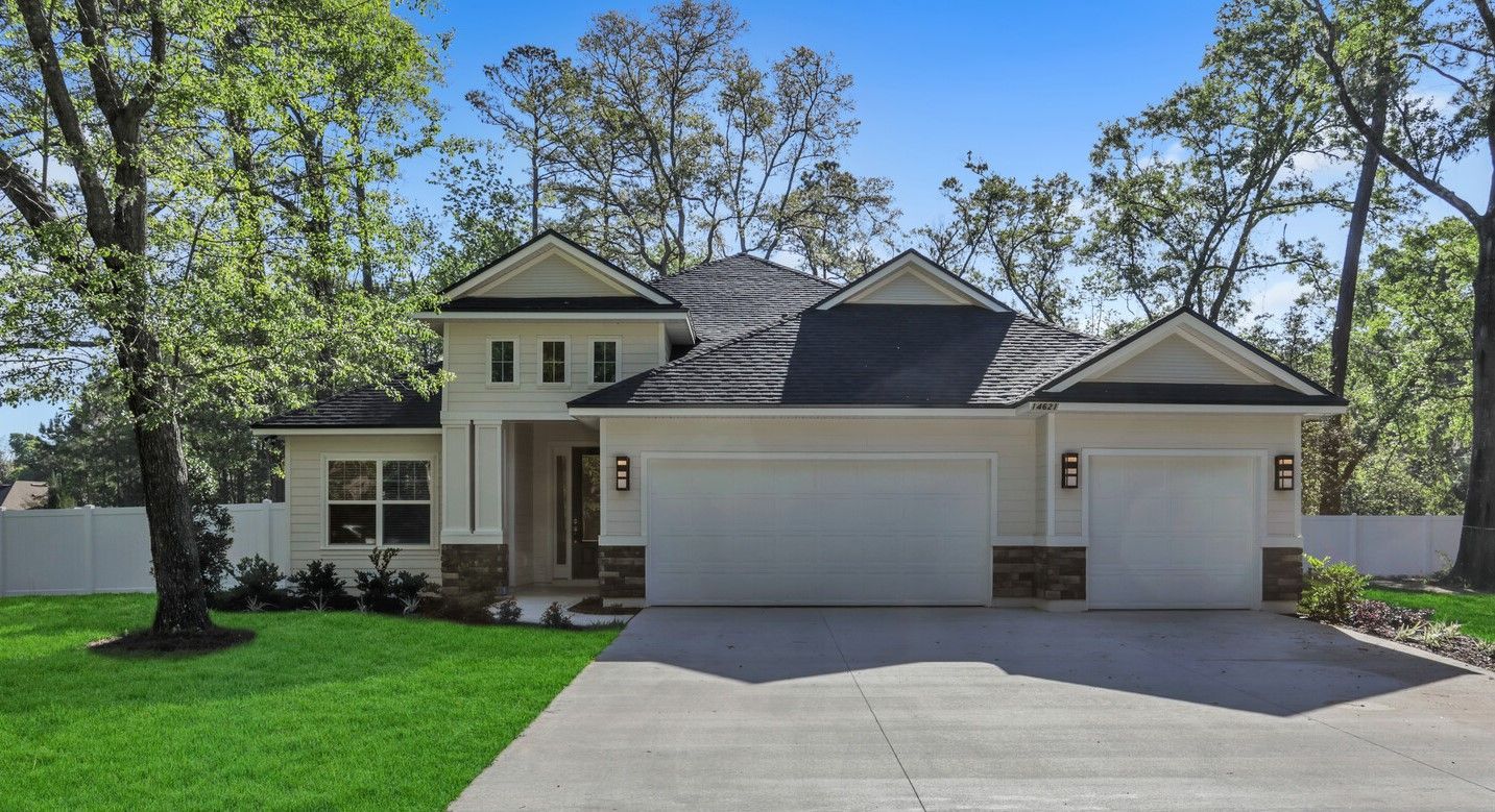 A white house with a black roof and a white garage door