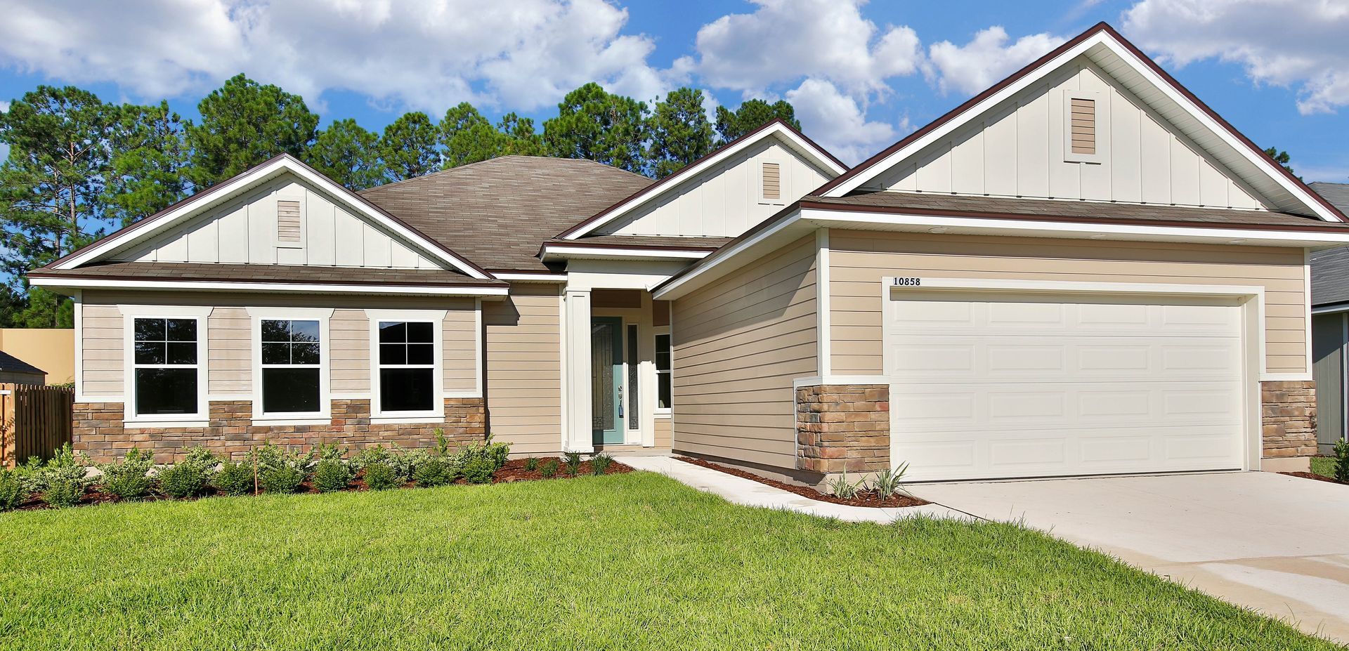 A large house with a white garage door is sitting on top of a lush green lawn.