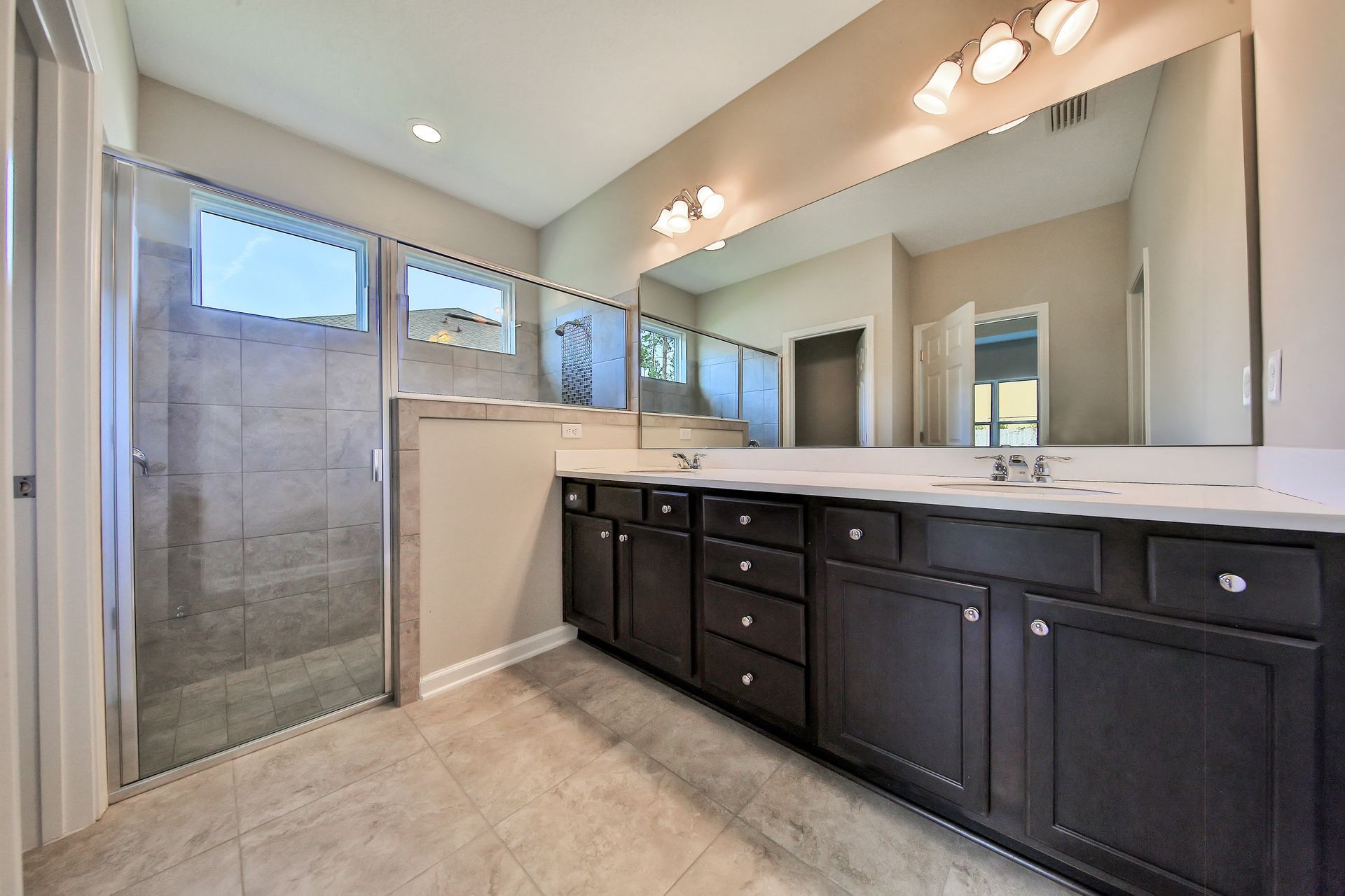A bathroom with two sinks and a walk in shower.