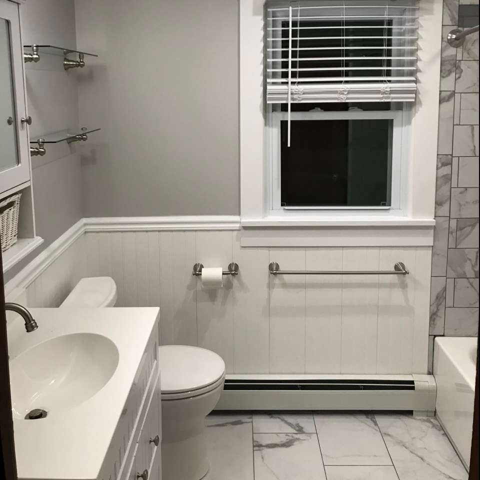 Bathroom with white walls, marble-look floor and tile, and a window with blinds.