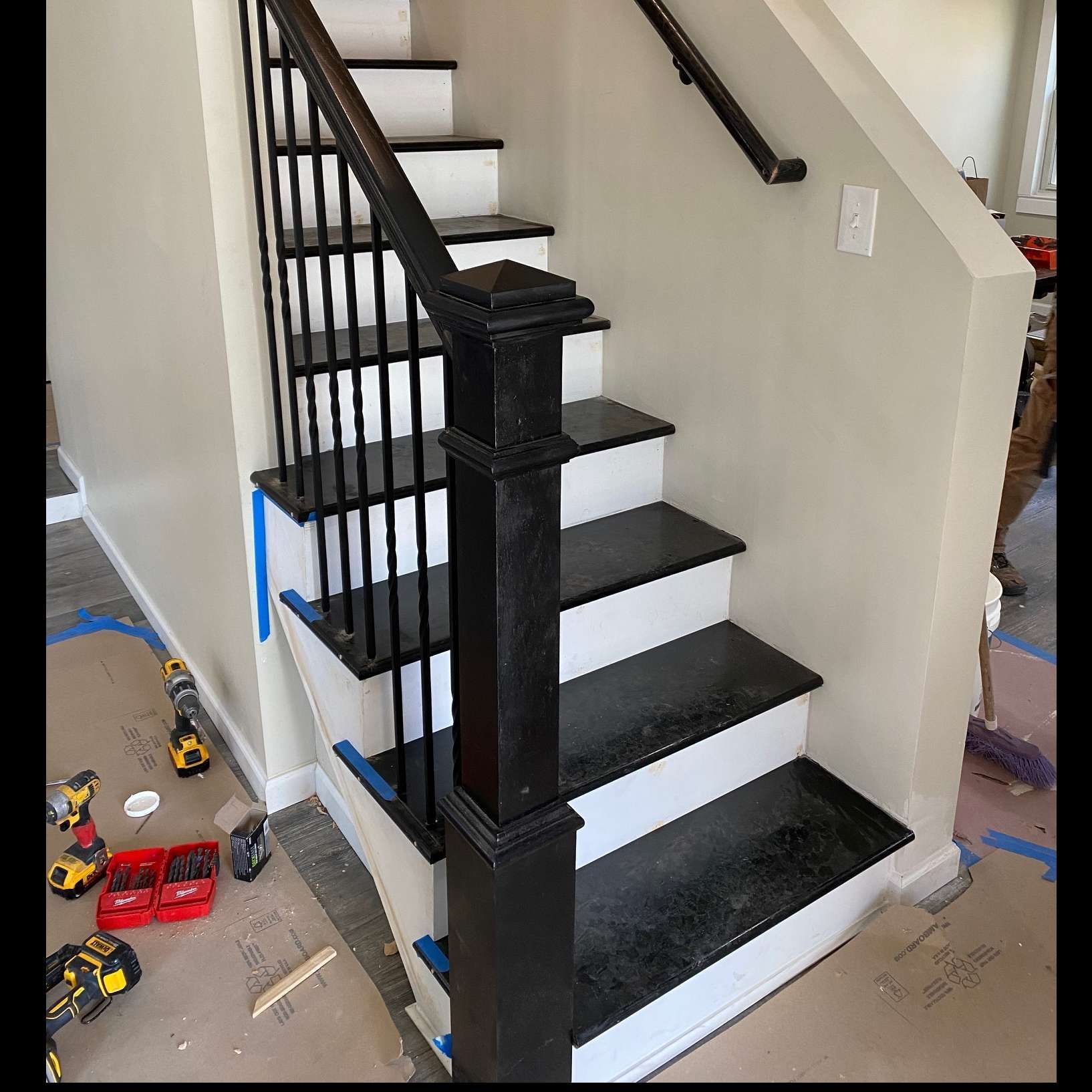 Black and white staircase with dark spindles and post, white risers, in a house.