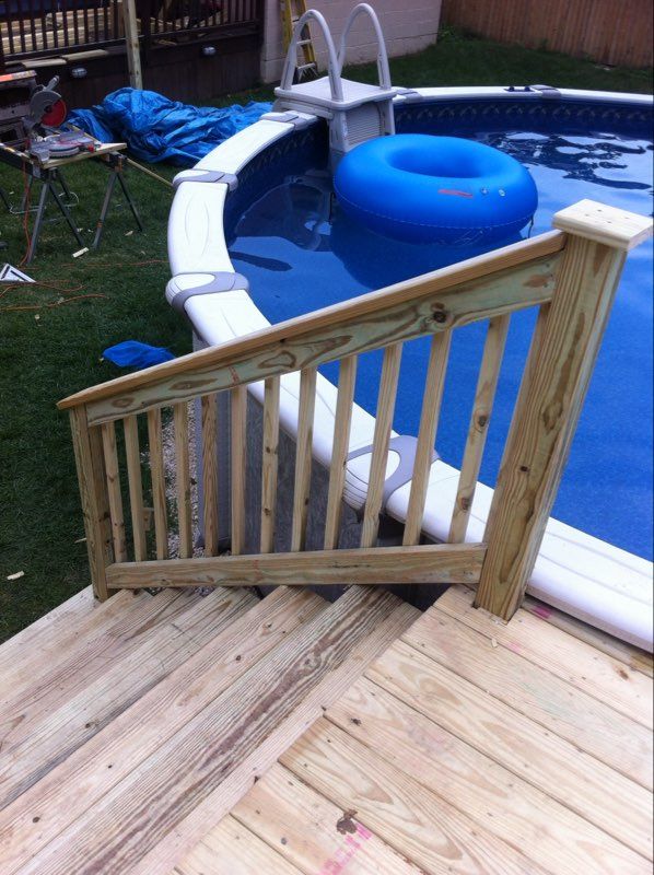 Wooden handrail and steps leading to a swimming pool with a blue floaty.