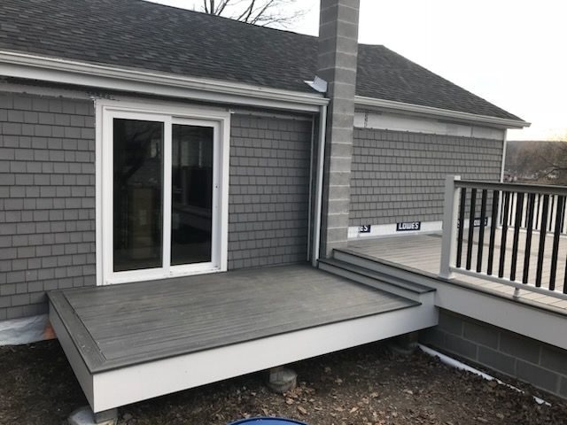 Gray shingled house with a deck and sliding glass door. 