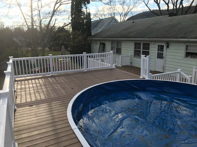 Brown deck surrounds a covered blue pool; white railing borders. 