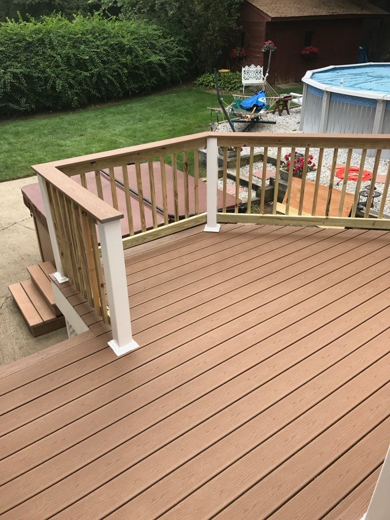 Composite deck with railing and steps, leading to a hot tub. 