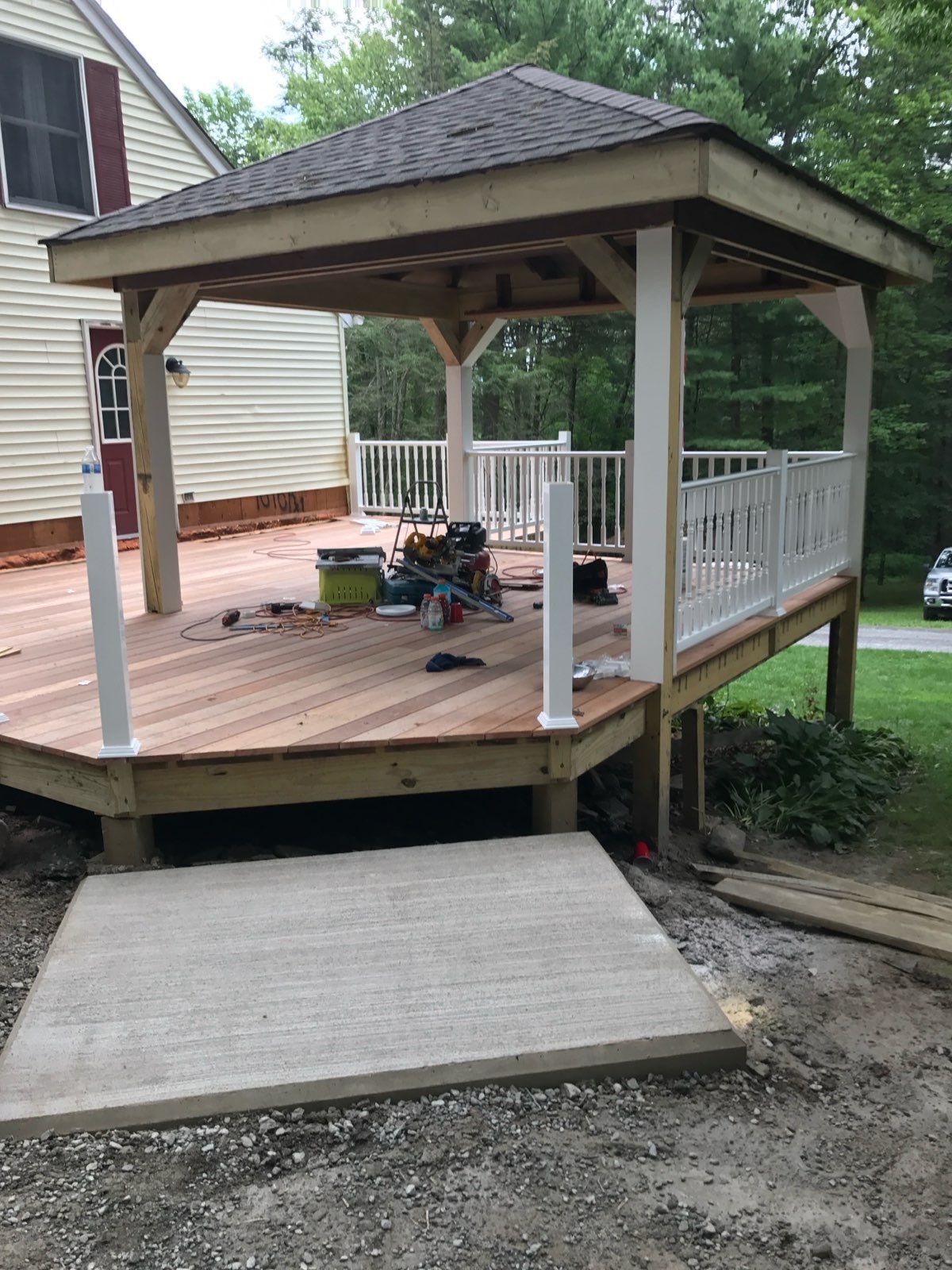 New deck with a gazebo and ramp; tan wood, white railing, gray concrete ramp.