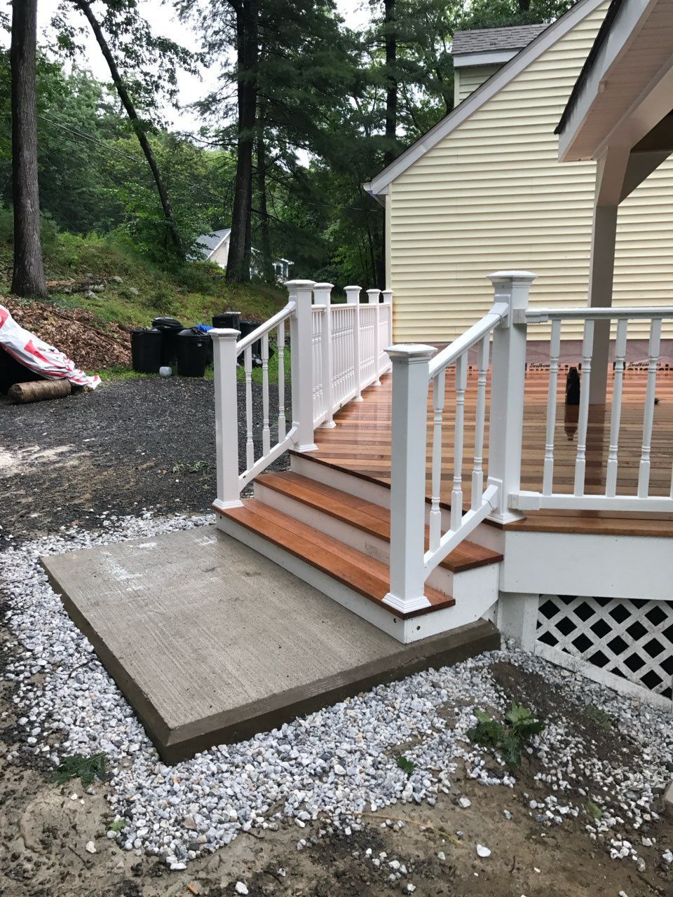 Newly constructed wooden deck with white railing and concrete ramp.