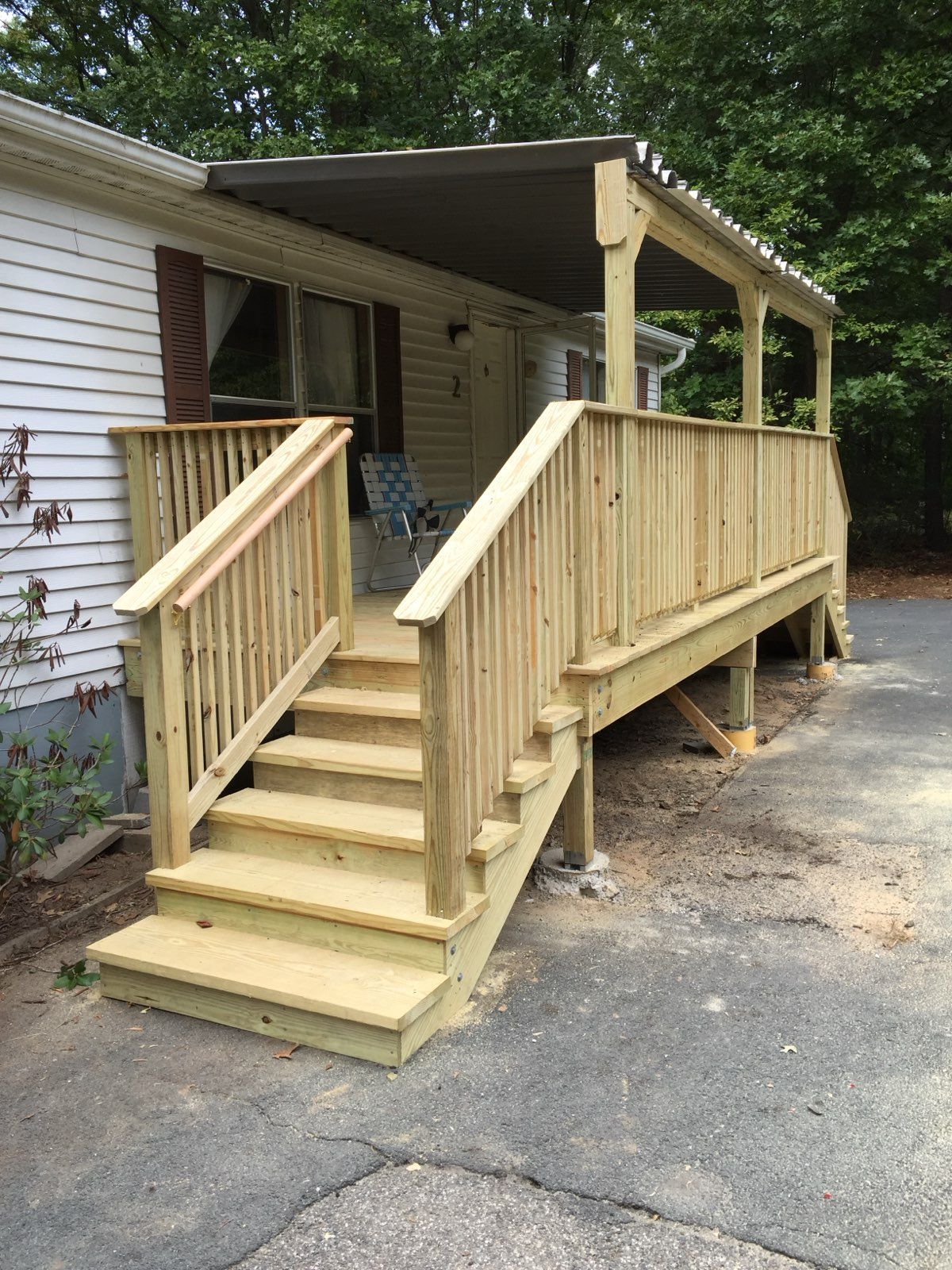 Wooden porch and steps leading to a house with a dark awning.