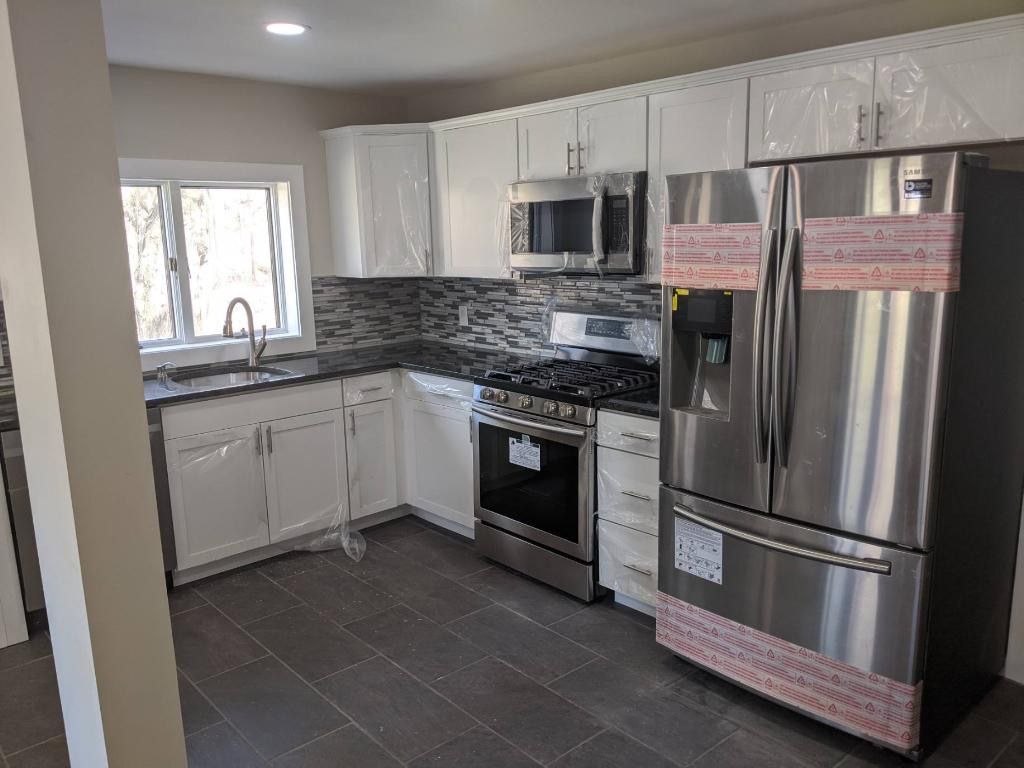 Newly renovated kitchen with white cabinets, stainless steel appliances, and dark gray countertops.