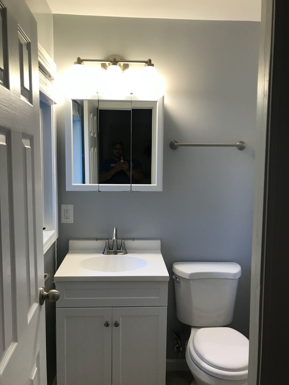 Small bathroom with white vanity, toilet, and mirror above the sink. 