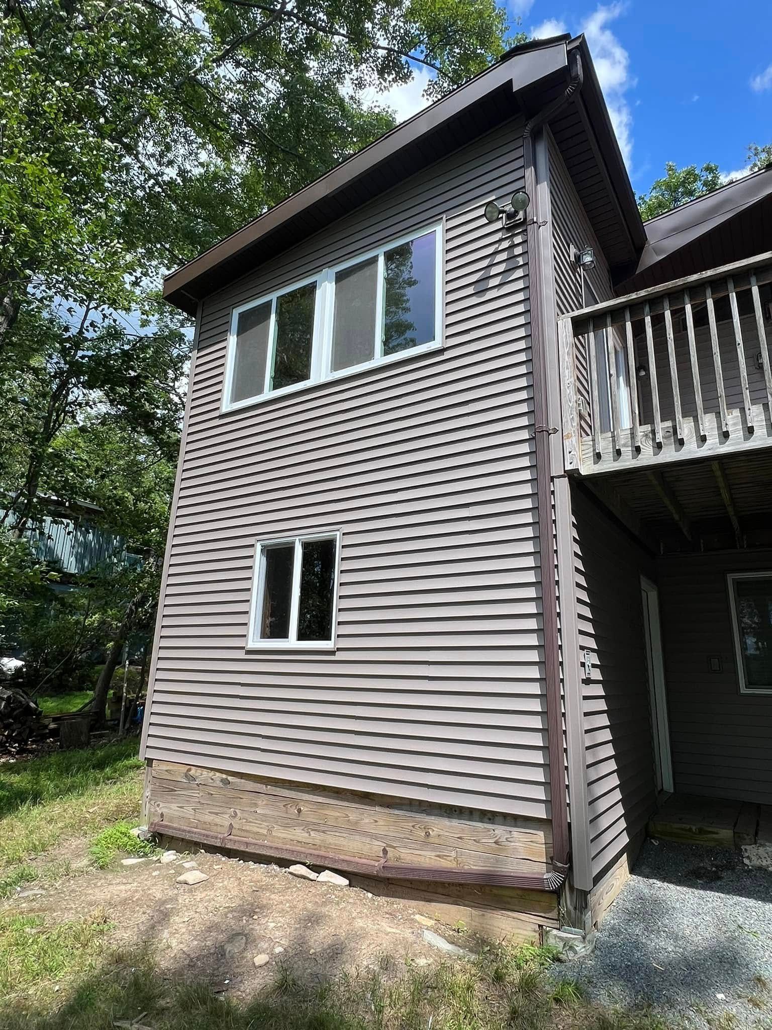 Tan house exterior with brown trim, windows, and a deck.