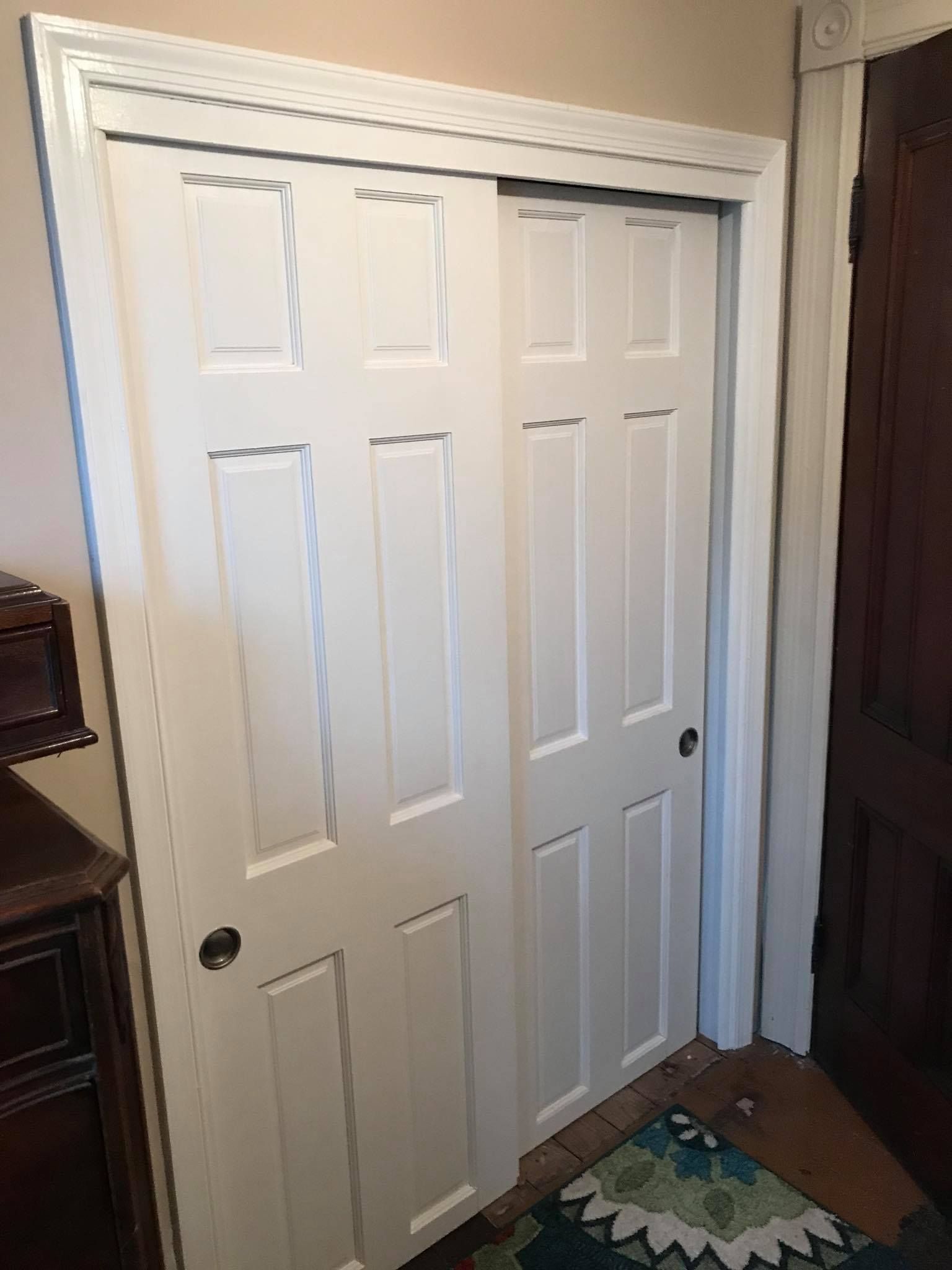 White sliding closet doors with white trim and a dark handle.