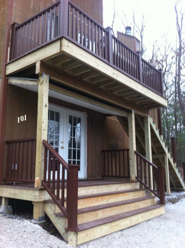 Brown building with a two-level deck, stairs, and a doorway.