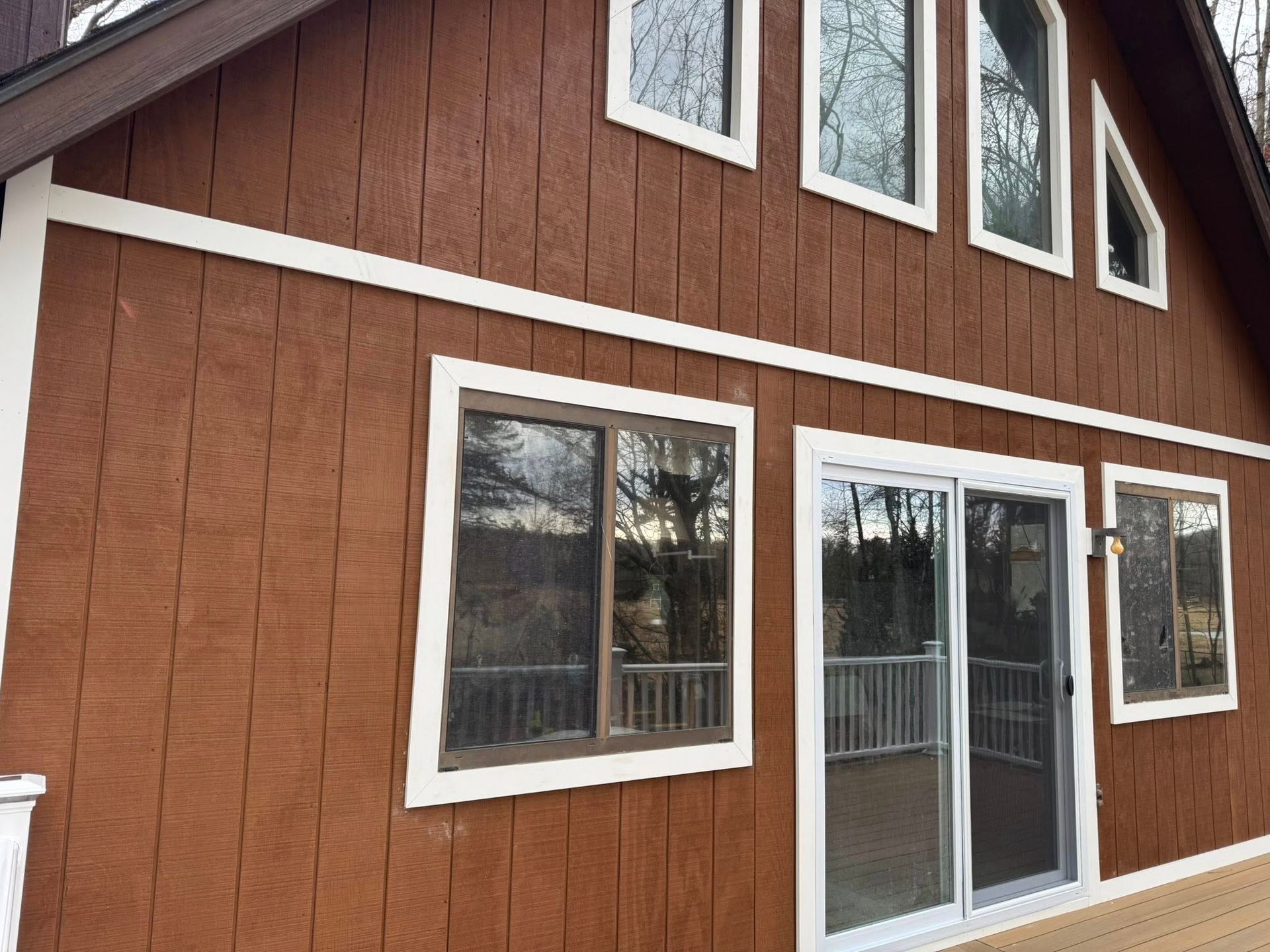Brown house with white trim, windows, and a sliding glass door.