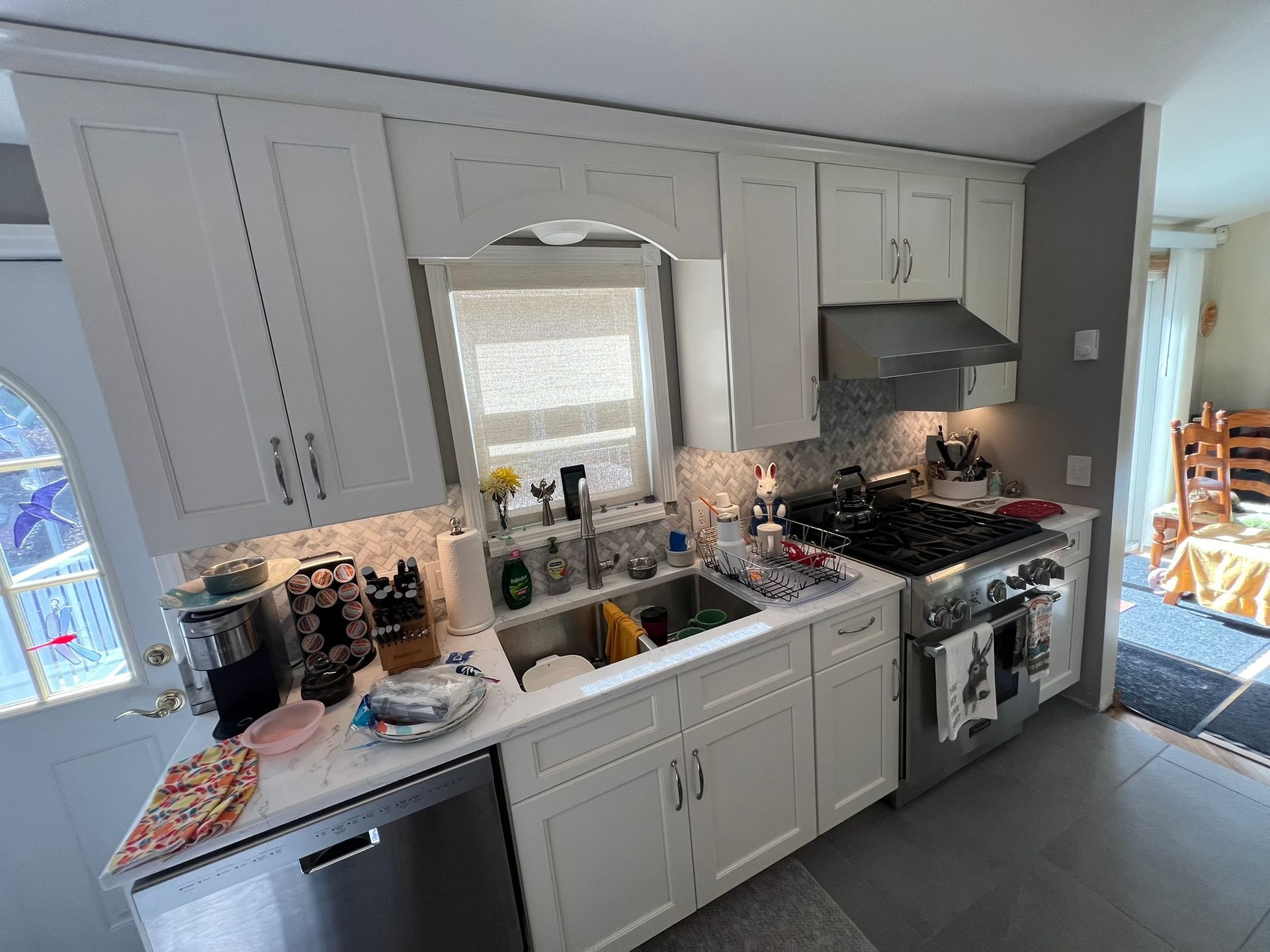 White kitchen with cabinets, stainless steel appliances, and a window.