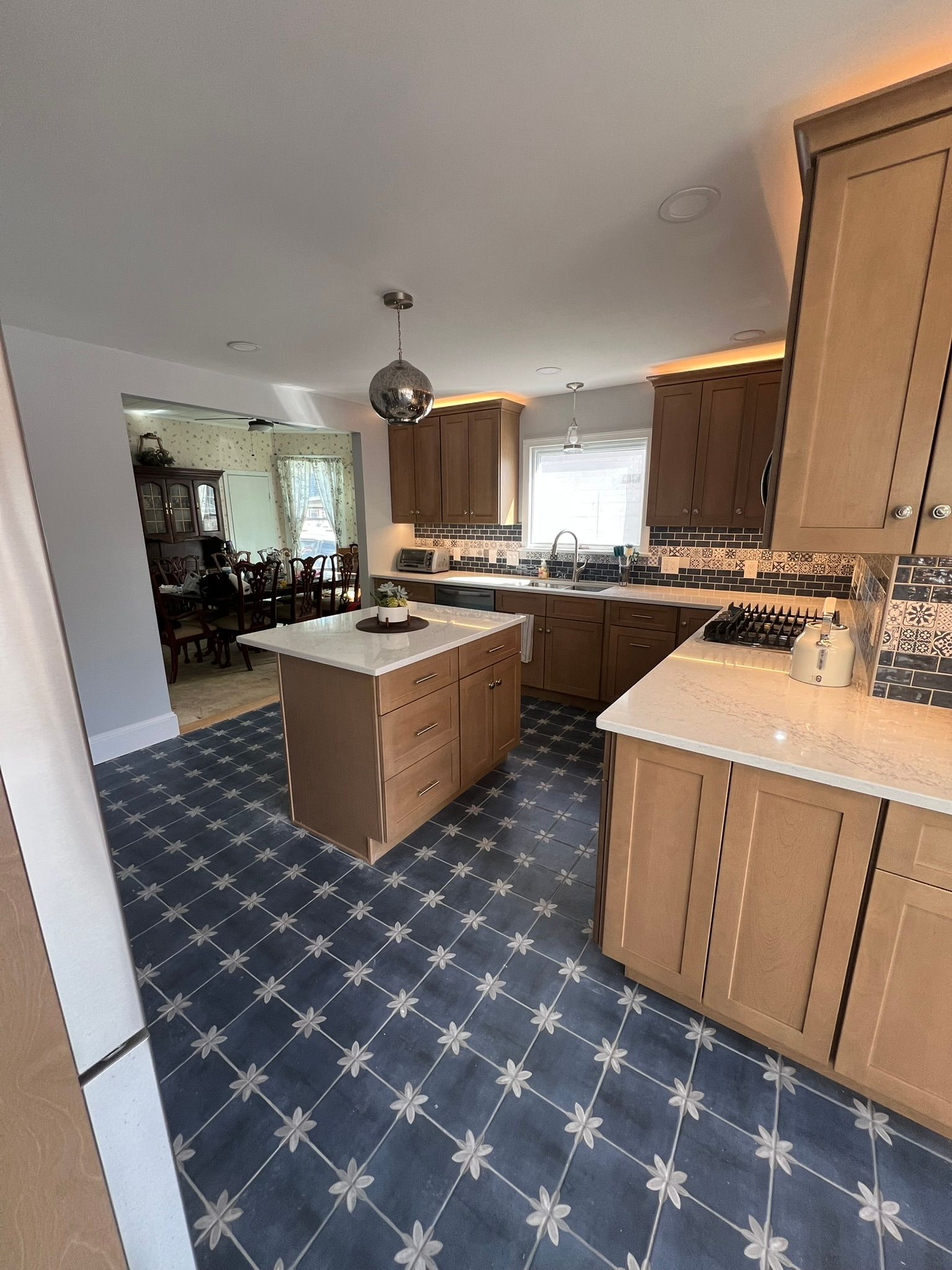 Kitchen with light wood cabinets, an island, and blue patterned floor.