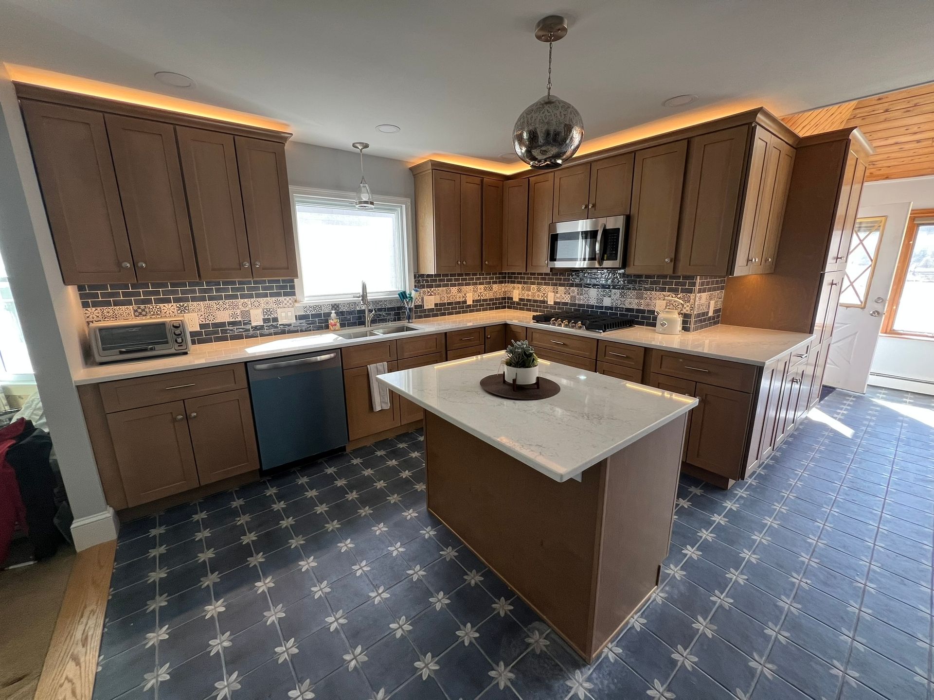Modern kitchen with wood cabinets, island, blue patterned floor, and a mirror disco ball.