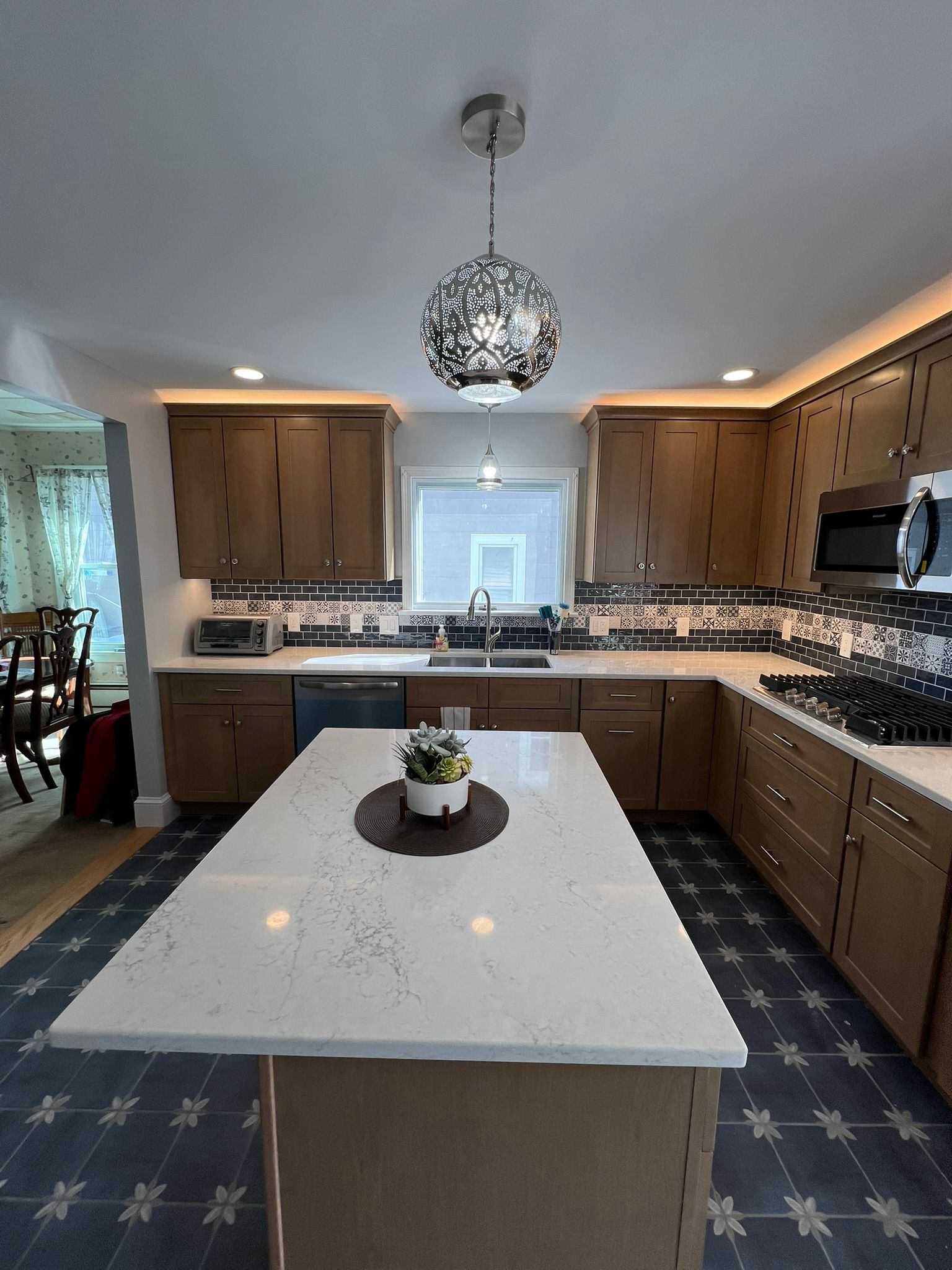 Kitchen with light wood cabinets, white island, and patterned blue floor.