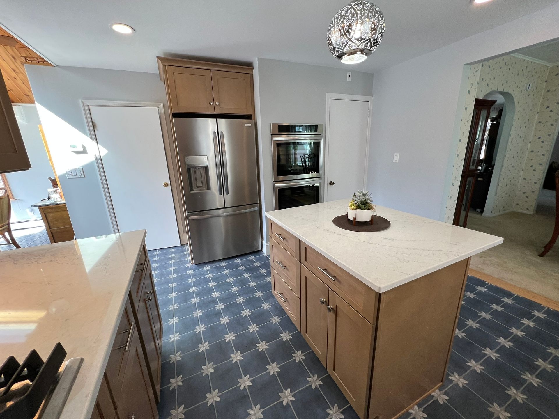 Kitchen with island, stainless steel refrigerator, and patterned blue tile flooring.