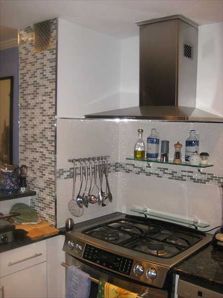 Stainless steel range hood above a gas stove in a kitchen. 