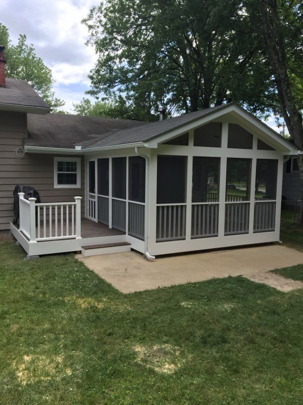 Screened-in porch attached to a house with white railing and trim.