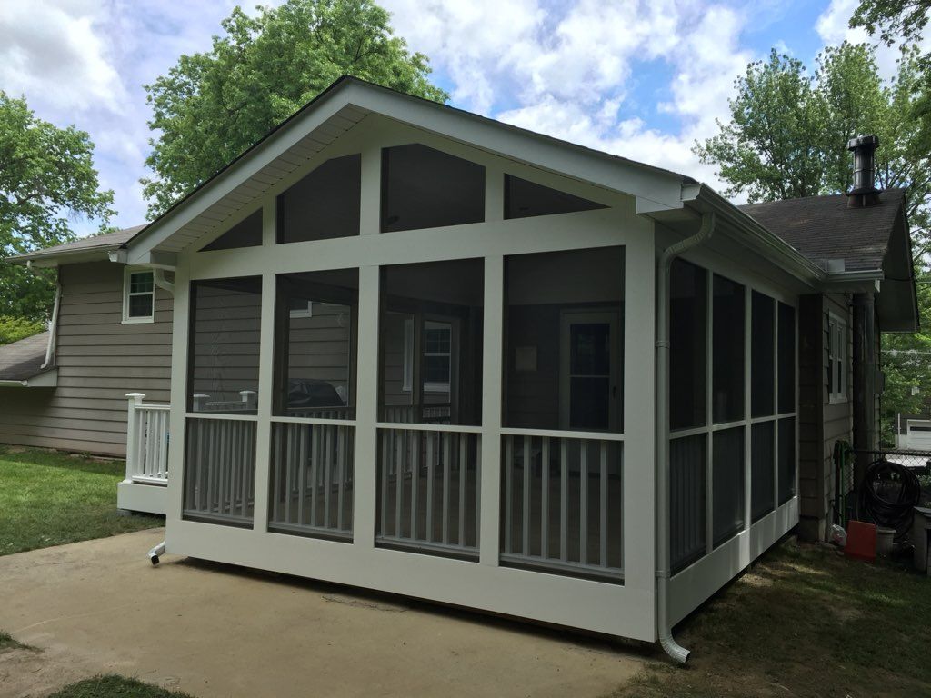 Screened-in porch addition with white trim, gray siding, and a sloped roof.