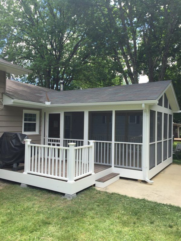 Screened-in porch addition with white railing and trim, attached to a house with a deck and patio.