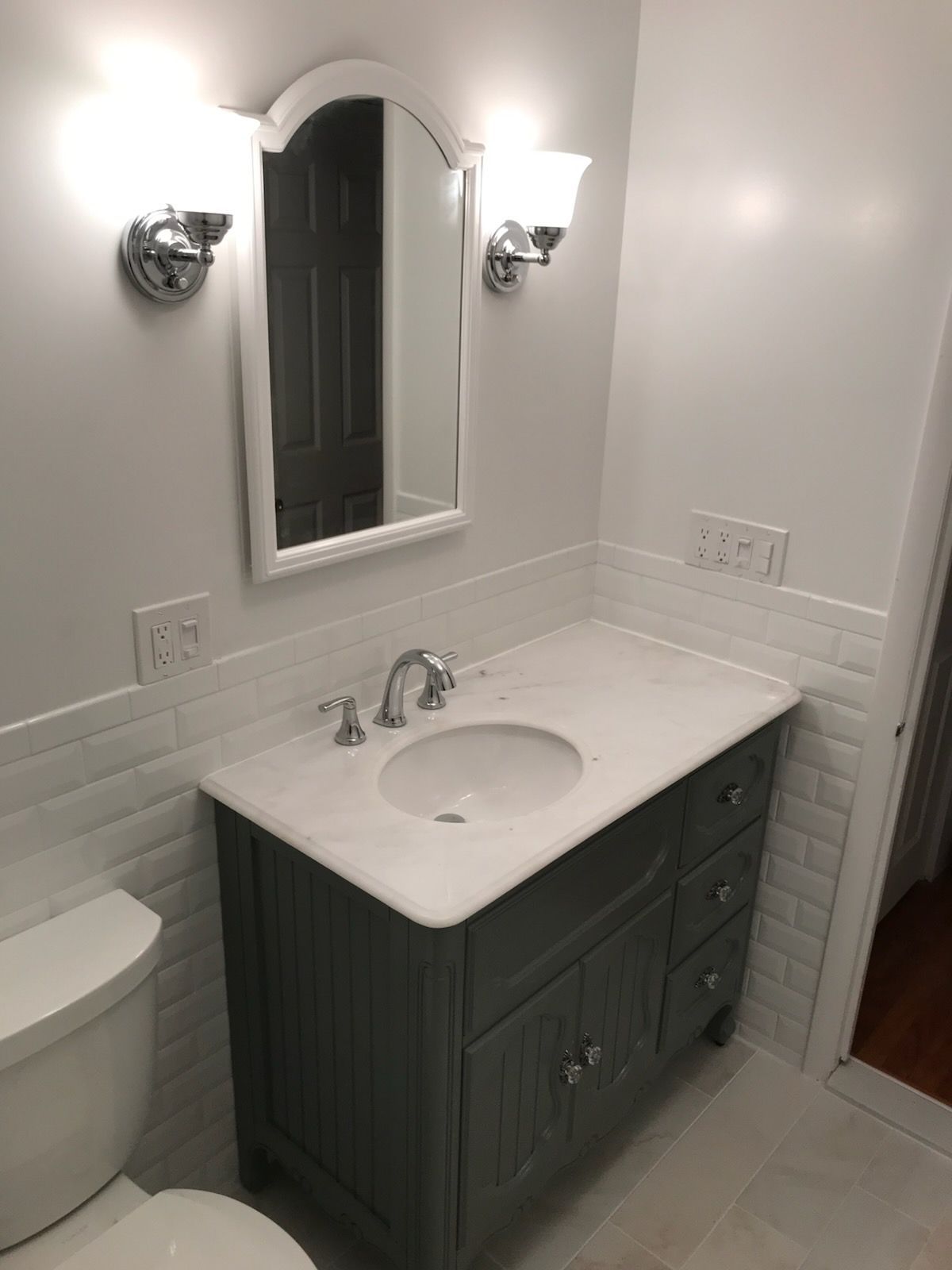 Bathroom with gray vanity, white countertop, oval sink, and mirror; white walls.