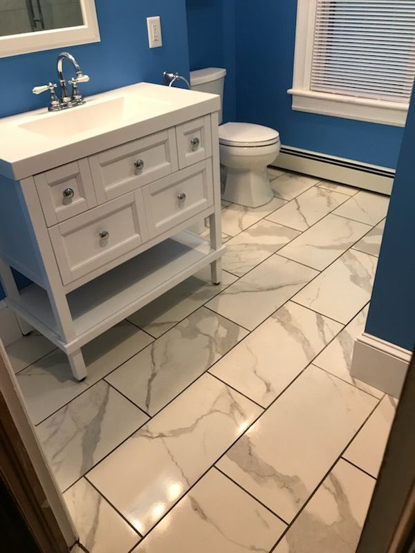 Bathroom with white vanity, toilet, and marble-look floor; blue walls.