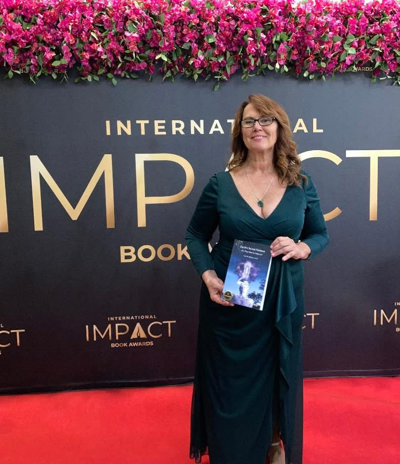 Woman in green dress holds book, standing on red carpet at 