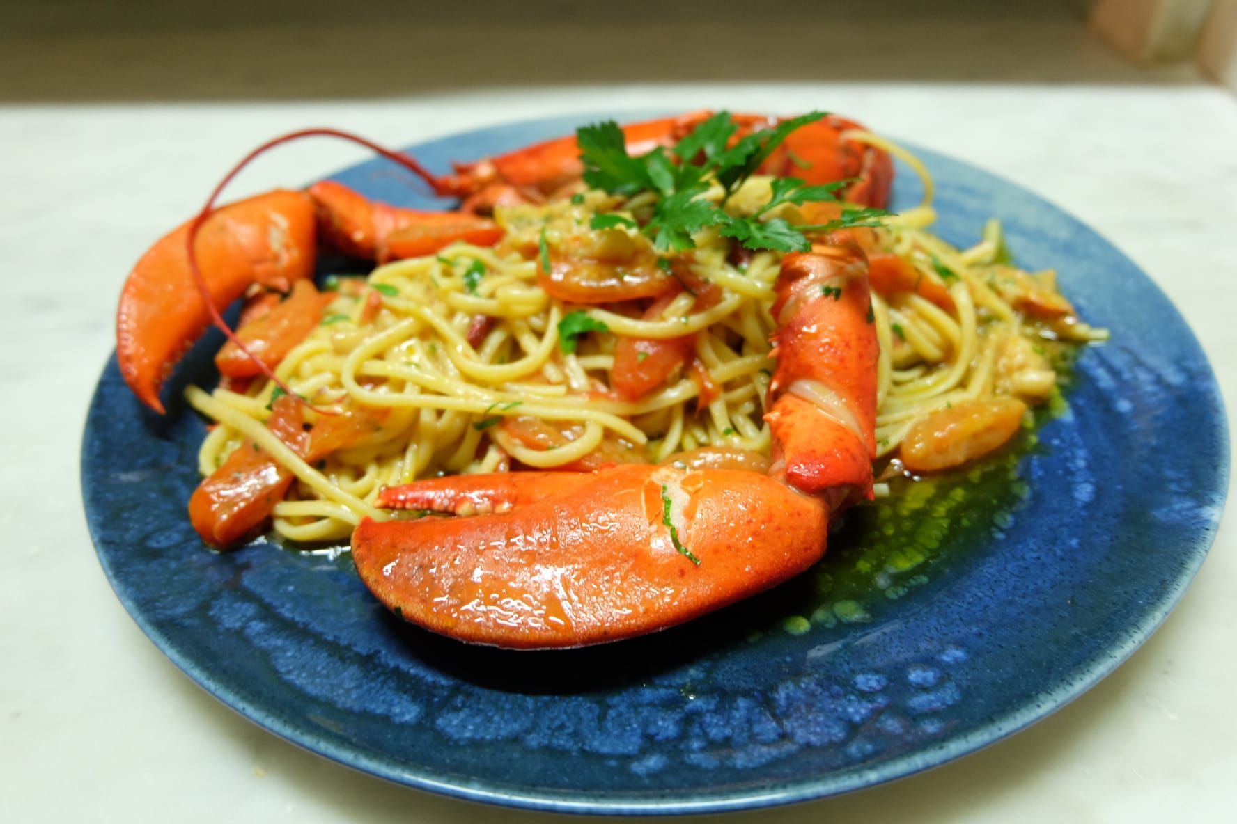un primo piano di un piatto di spaghetti e aragosta su un tavolo .