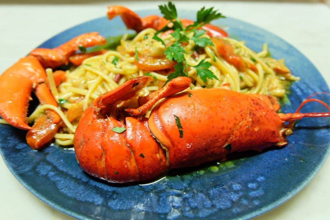 un primo piano di un piatto di aragosta e spaghetti su un tavolo