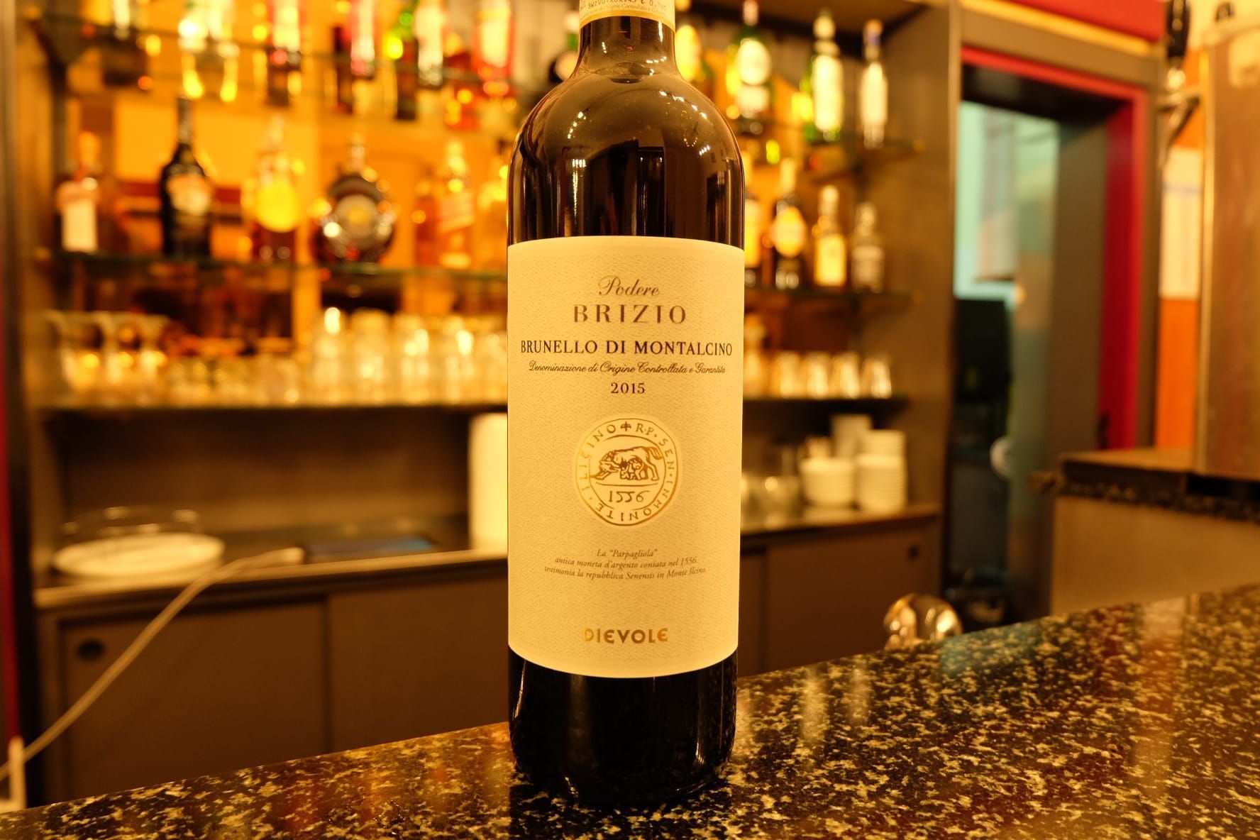 una bottiglia di vino è seduta su un bancone in un bar .