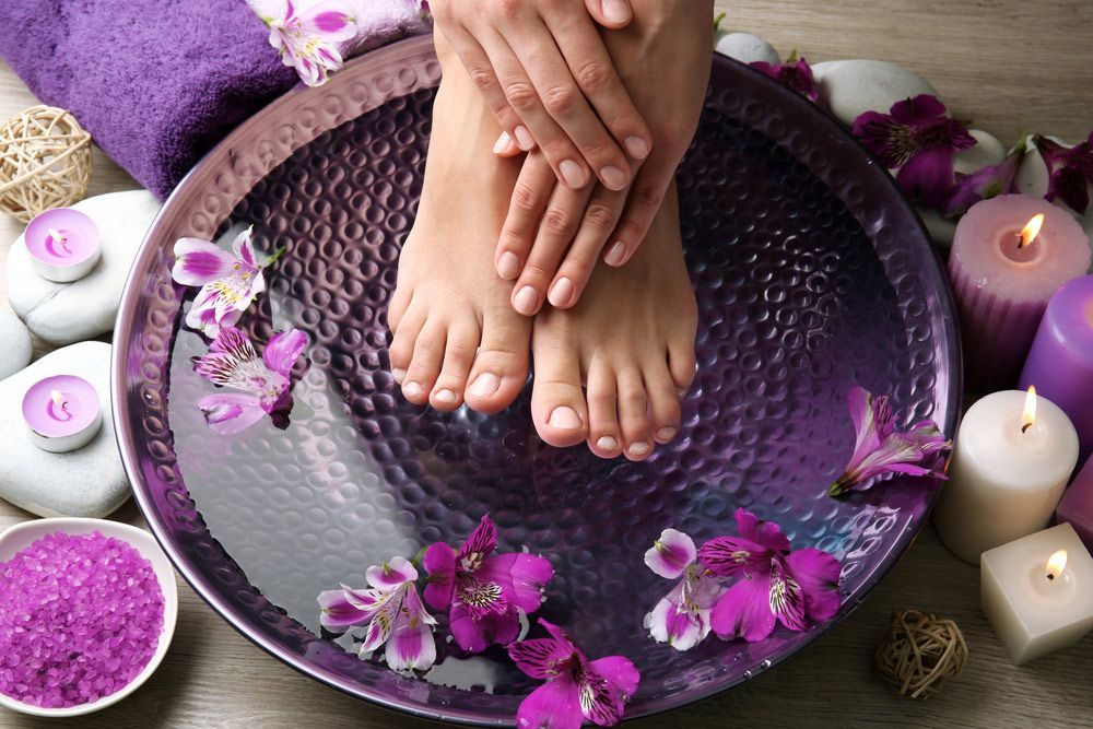 A Woman's Feet Are Sitting In A Bowl Of Water With Flowers And Candles — Sandy Gugenberger Podiatrist in Port Macquarie, NSW