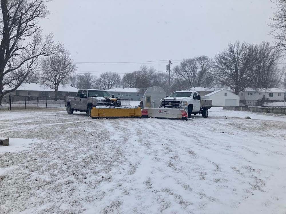 Two trucks are parked in a snowy parking lot.