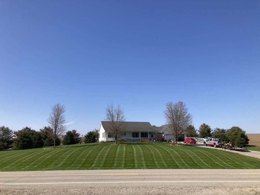 A white house is sitting on top of a lush green field.