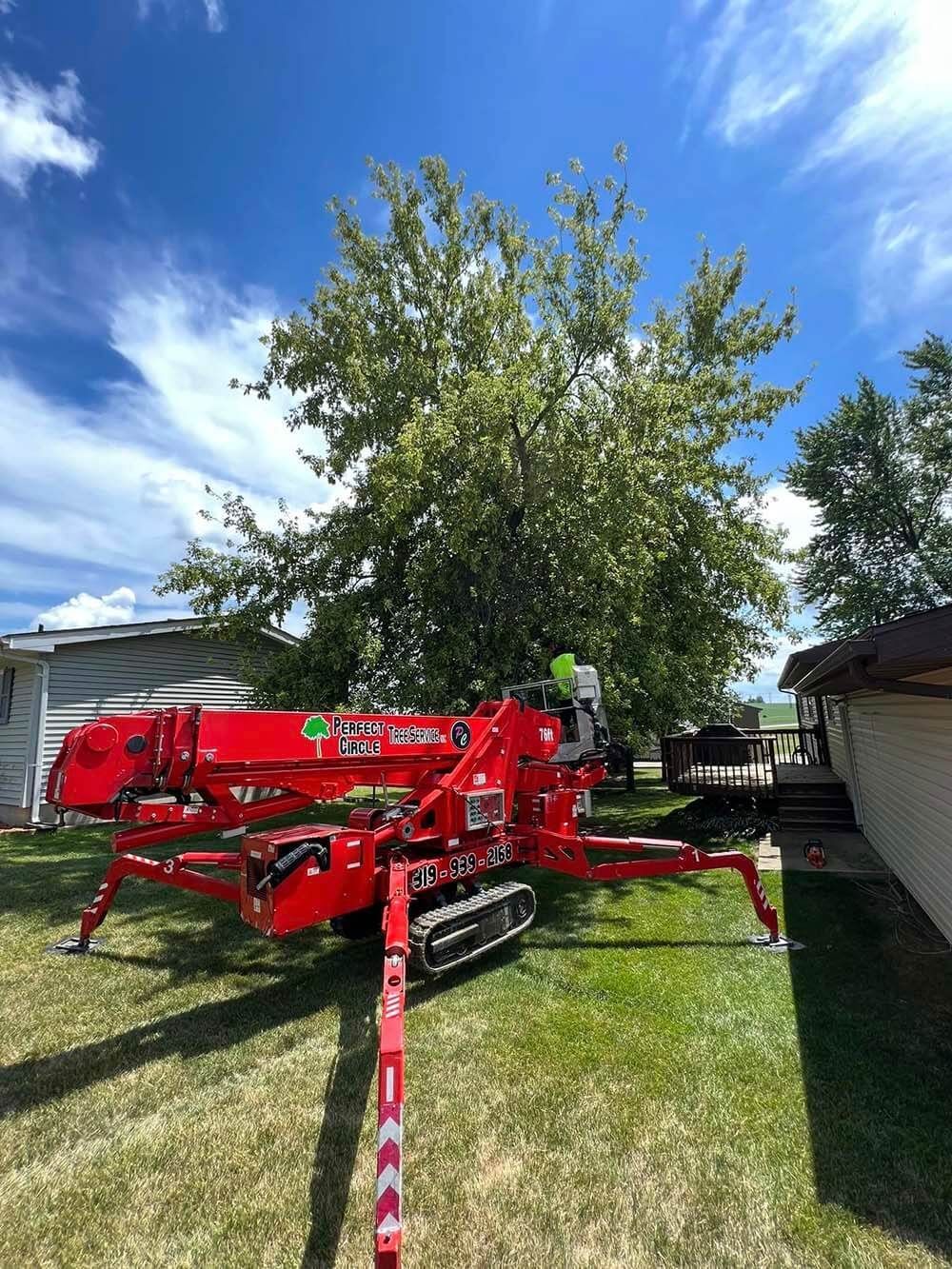 A red crane is sitting in the grass in front of a house.