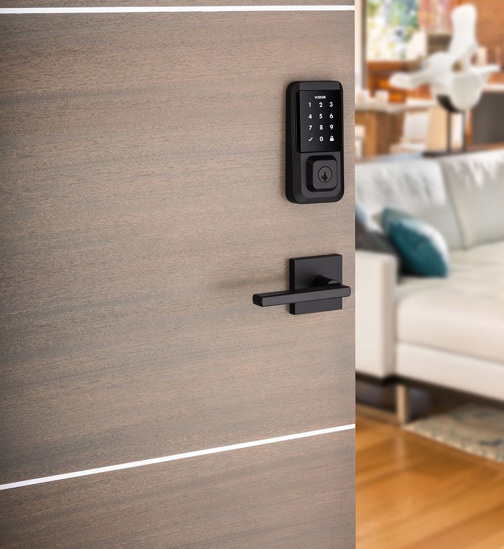 A door with a digital lock on it and a couch in the background.