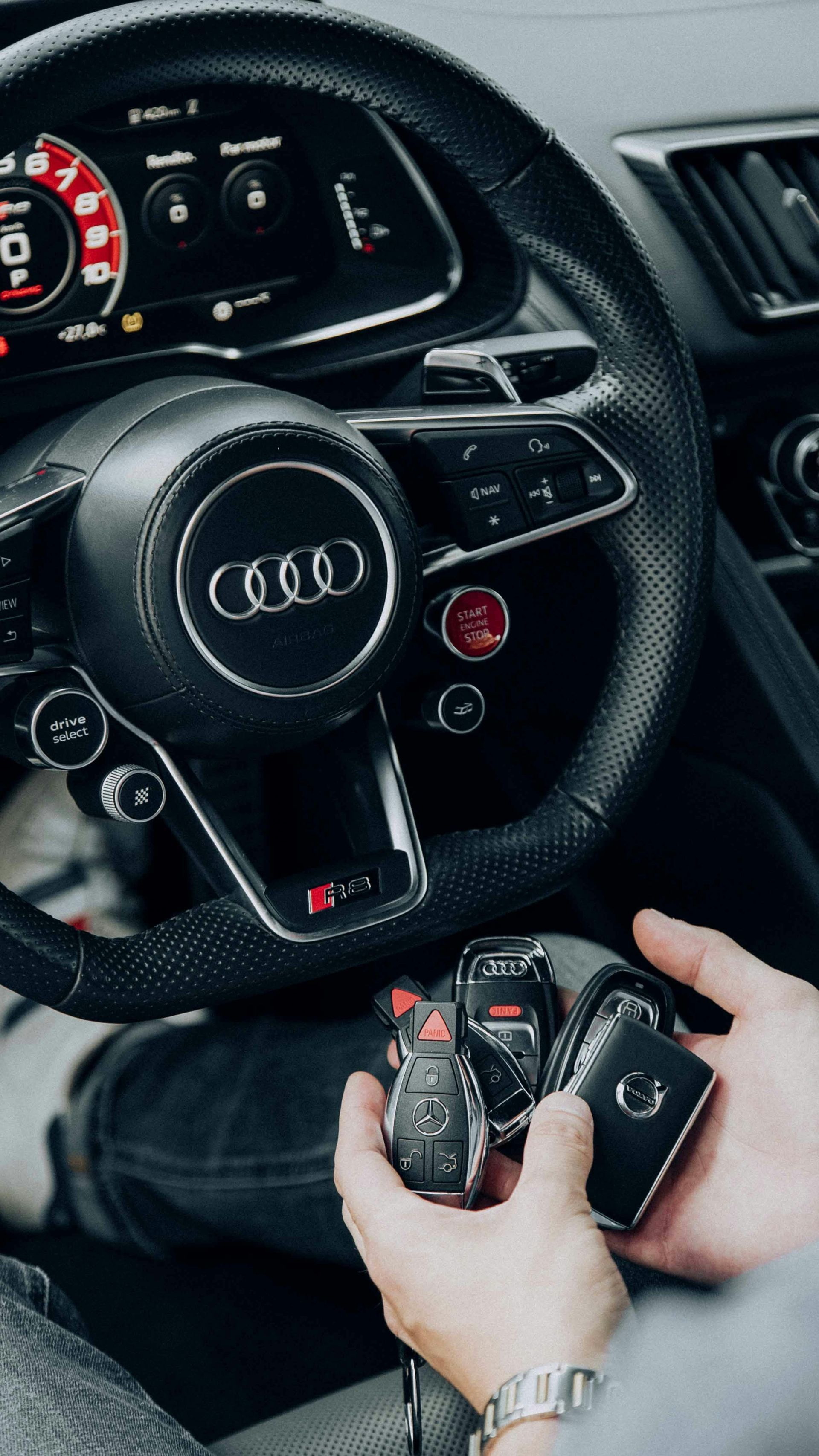 A person is holding a remote control in front of a red car.