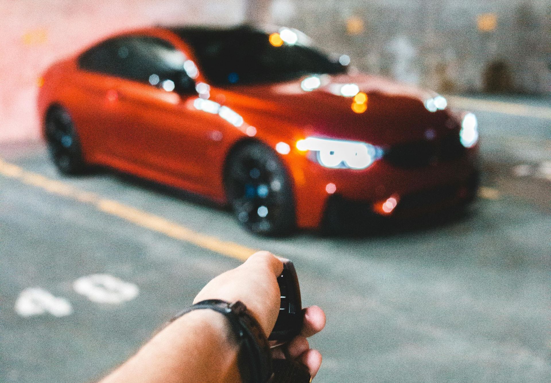 A person is holding a pair of keys in front of a red car.