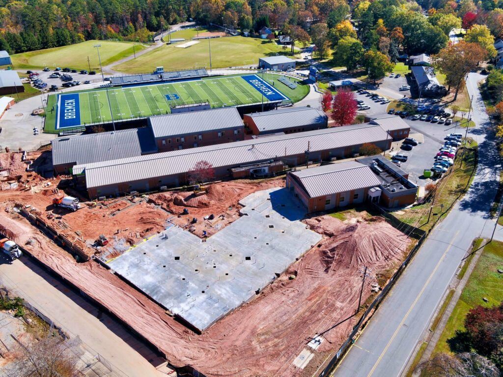 An aerial view of a school with a football field in the background.