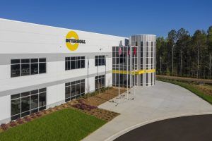 An aerial view of a large white building with a yellow logo on it.