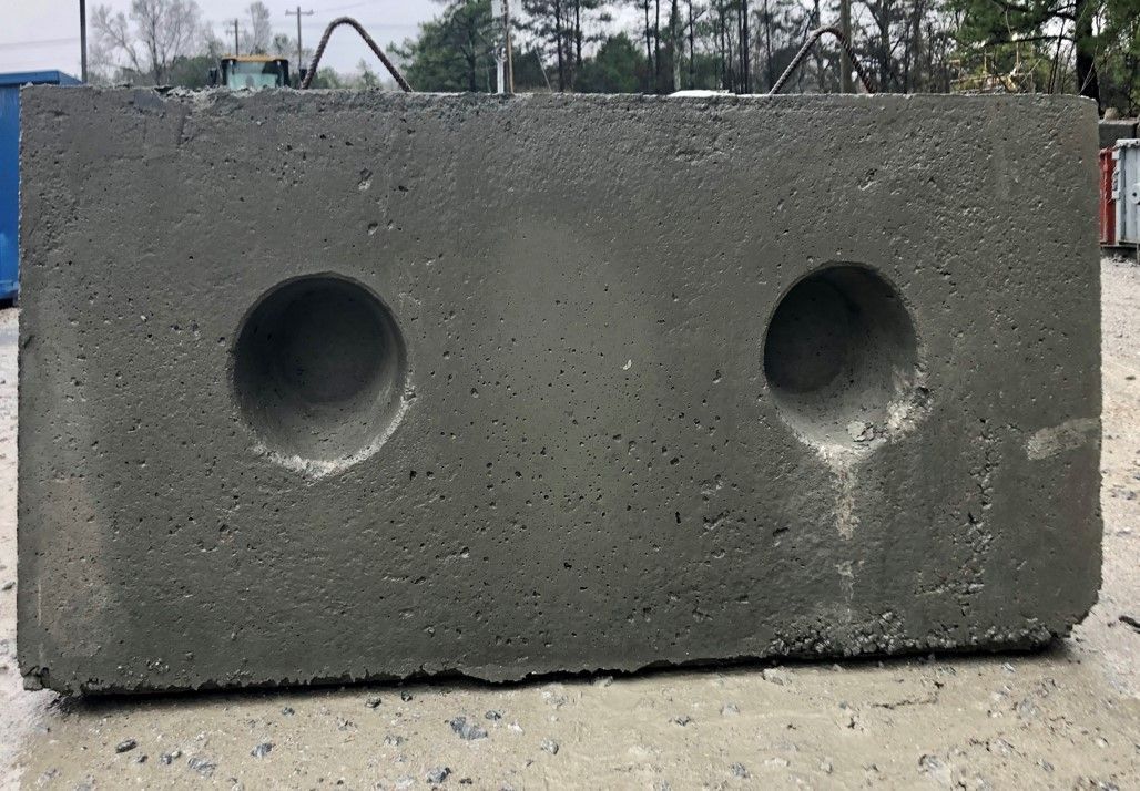A concrete block with two holes in it is sitting on the ground.