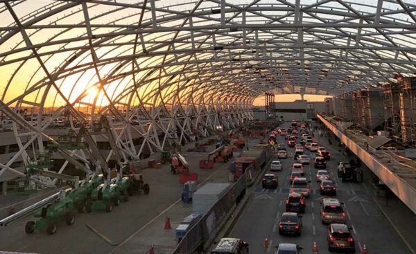 A lot of cars are driving down a highway under a bridge at sunset.