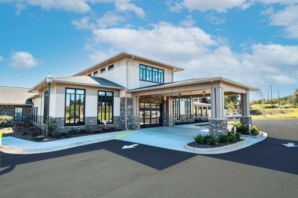 A large white house with a lot of windows and a parking lot in front of it.