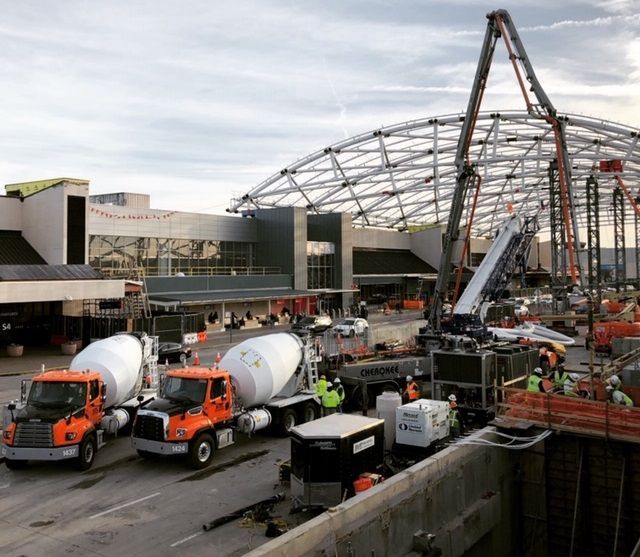 Several trucks are parked in front of a building under construction