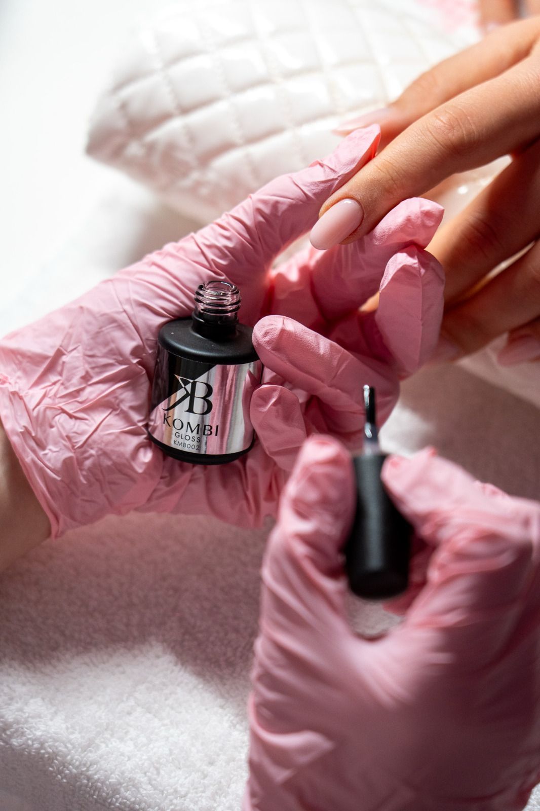 Una persona che indossa guanti rosa sta applicando lo smalto sulle unghie di un'altra persona.