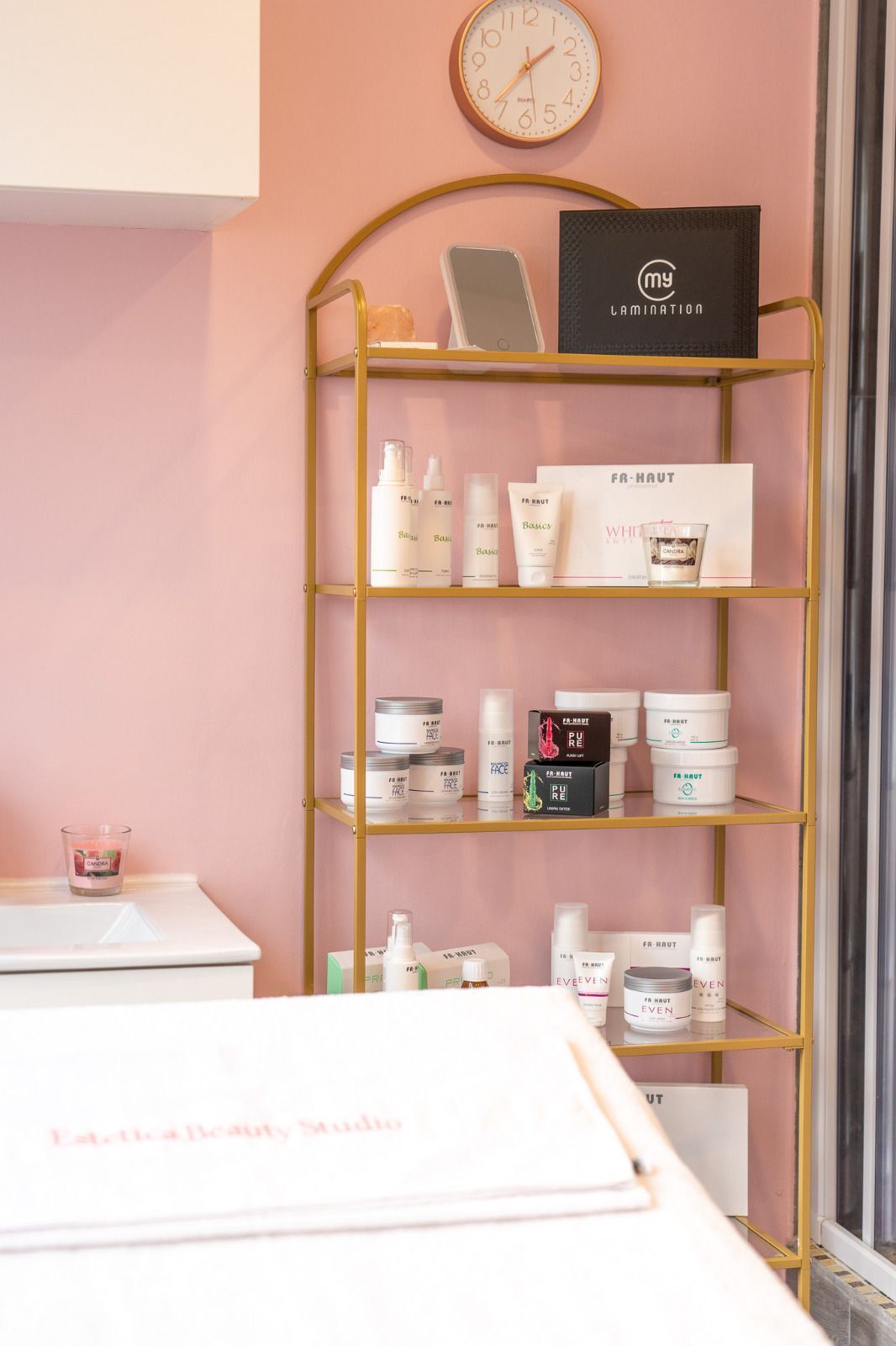 Uno scaffale pieno di cosmetici e un orologio sul muro.